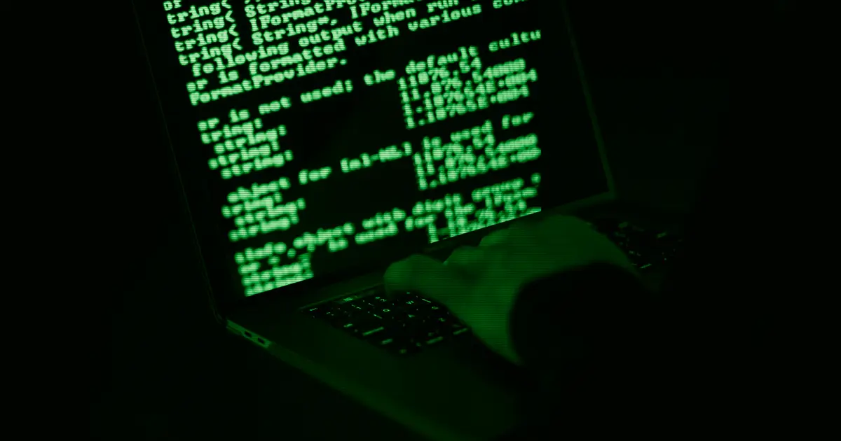 Manos escribiendo en un portátil con información en la pantalla