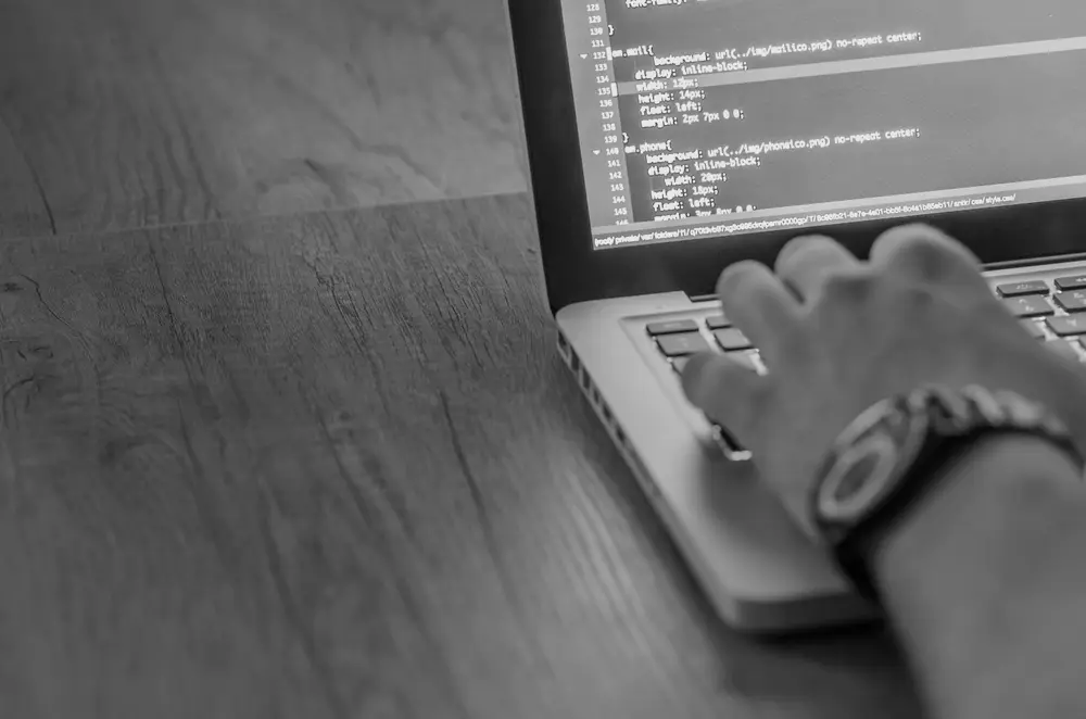 Persona desarrollando una web en un portátil con código en pantalla