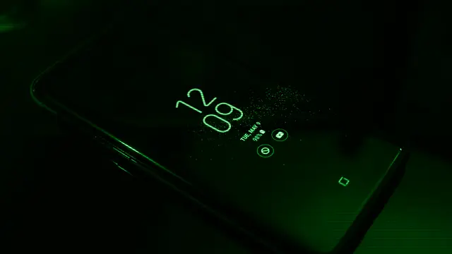 Pantalla de un smartphone encendido en la oscuridad con el reloj y las notificaciones, que ilustra la interfaz Liquid Glass de OriginOS 7